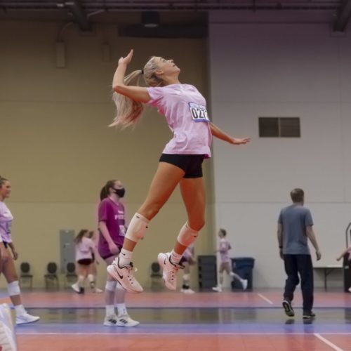 Woman jumping gloriously in the air, preparing to hit a volleyball